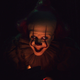 Pennywise, the clown from It, grins under red lighting.